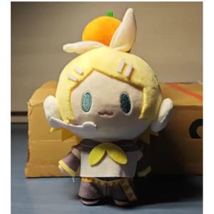May include: A plush doll featuring a character with yellow hair, teal eyes, and a small orange hat. The doll wears a white top with a yellow bow and a purple and brown outfit. The doll has white ears and is standing.