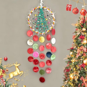 以下が含まれることがあります： 中央にクリスマスツリーのデザインが施された装飾的なドリームキャッチャー。白いウェブ、カラフルなビーズ、吊り下げられた赤、ピンク、緑の円形オーナメントが特徴です。ドリームキャッチャーは灰色の背景に吊り下げられており、右側には装飾されたクリスマスツリーがあります。