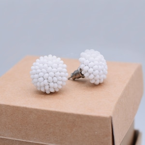 May include: A pair of white beaded stud earrings. The earrings are round and have a cluster of small white beads.