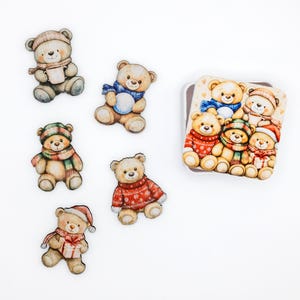 May include: A collection of five individual teddy bear die-cut stickers and one square tin featuring a group of teddy bears. The bears are illustrated in various winter outfits, including sweaters, scarves, and hats, with some holding mugs, gifts, or snowballs.