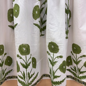 Puede incluir: Tela blanca con un patr&oacute;n repetido de dise&ntilde;os florales verdes. El dise&ntilde;o incluye flores grandes y redondas y hojas detalladas. La tela tiene un borde con un patr&oacute;n verde y azul y est&aacute; adornada con borlas blancas.