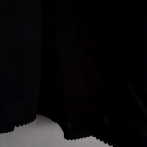 May include: Black underwear with a scalloped lace trim along the edges. The fabric appears to be a soft, opaque material. The image is a close-up of the garment.