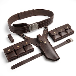 Op de afbeelding: Een bruine leren riem met zilveren gesp, vergezeld van een holster, pouches en riemen. De set bevat meerdere pouches met messingkleurige knoopsluitingen en een kleine riemlus. Het leer is een rijk, donkerbruin.