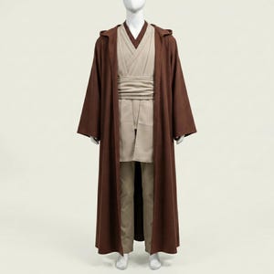 May include: A brown hooded robe with long sleeves, worn over a beige tunic and pants. A beige sash is wrapped around the waist. The outfit is displayed on a mannequin.