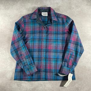 May include: A button-down plaid shirt in shades of teal, purple, and pink. The shirt has a collar, long sleeves, and a tag that reads "Pendleton". The shirt is made of a soft, woven fabric.