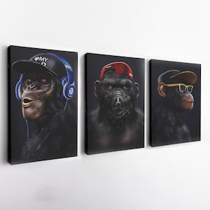 May include: Three canvas art prints featuring chimpanzees with human-like accessories. One chimp wears a black cap and headphones, another a red cap and mask, and the last a cap and yellow-framed glasses. All are set against a dark background.