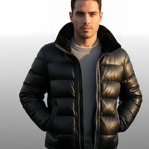 May include: A black quilted puffer jacket with a large collar and a zip. The jacket has two front pockets. The person in the image is wearing a grey sweater. The jacket is a stylish outerwear garment.