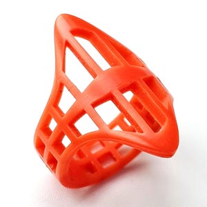 May include: A vibrant orange ring with a geometric, cage-like design. The ring features a series of interconnected rectangular openings, creating an open and airy aesthetic. The ring is made of a solid material and has a smooth, matte finish.