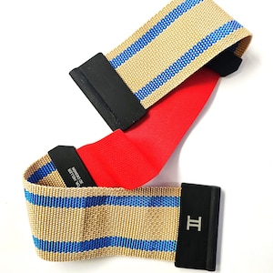 Puede incluir: Dos correas beige y azul a rayas con cierres rectangulares negros y una correa roja en el medio. Un cierre tiene la letra "H" grabada, y otro el texto "DR. HELLER 3D DESIGN".