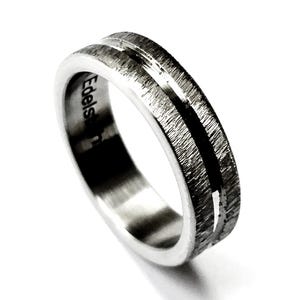 Könnte beinhalten: Ein silberner Ring mit strukturierter Oberfläche und einer zentralen Rille. Der Ring hat ein gebürstetes Metall-Aussehen und das Wort "Edels" ist seitlich eingraviert. Der Ring ist vor einem weißen Hintergrund platziert.