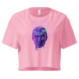 Peut inclure: Haut court rose avec un motif d'art numérique représentant un visage humain avec des équations mathématiques et des motifs de circuits imprimés violets et turquoise. Le motif est centré sur le devant.