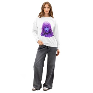 Könnte beinhalten: Weißes Sweatshirt mit Rundhalsausschnitt und einem lila-blauen Grafikdesign eines Frauengesichts mit einem gehirnartigen Design auf dem Kopf. Die Frau trägt ein lila-blaues Design im Galaxie-Stil. Das Model trägt eine graue Hose mit weitem Bein.
