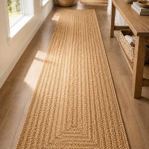 Peut inclure: Un long tapis de couloir rectangulaire fabriqué à partir de fibres tressées de couleur beige naturel. Le tapis présente une texture tissée uniforme avec un motif de bordure distinct créé par l'orientation des tresses sur le sol.