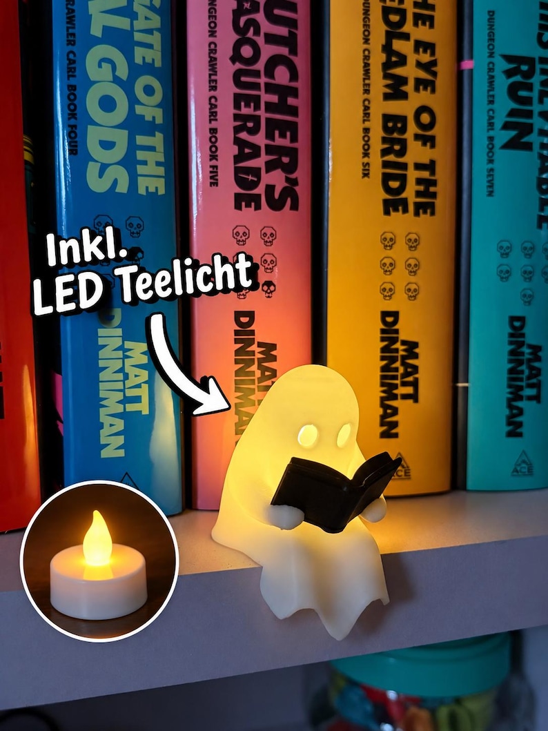 May include: A small, off-white, ghost-shaped figurine reading a black book, illuminated from within. A white arrow points to the text Inkl. LED Teelicht, with a circular inset showing a glowing, battery-operated LED tea light candle.