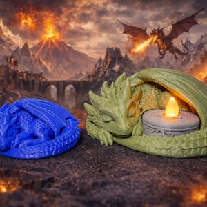 Könnte beinhalten: Zwei Drachenfiguren, eine blaue und eine grüne, liegen auf einer strukturierten Oberfläche. Der grüne Drache hält einen Kerzenhalter mit einer brennenden, gelben LED-Kerze. Eine Fantasielandschaft mit Vulkan und fliegenden Drachen bildet den Hintergrund.