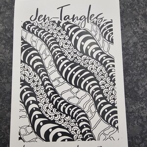 May include: A white card with the text "Jen-Tangles" and "Hand-drawn Coloring Pages." The card showcases a black and white abstract design with curved, striped shapes and intricate patterns, designed for colouring.