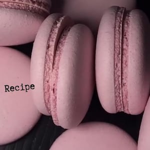 Könnte beinhalten: Nahaufnahme von mehreren rosa Makronen, einige ganz und andere geöffnet, die eine cremige Füllung zeigen. Der Text "Macarons Recipe" ist sichtbar. Diese französischen Köstlichkeiten sind ein Genuss.