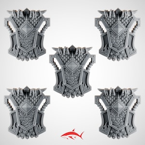 May include: Five gray, stylized chest armor pieces with intricate detailing. Each piece features a central diamond shape, textured surfaces, and decorative elements, including flames and horns. The pieces are arranged against a white background.