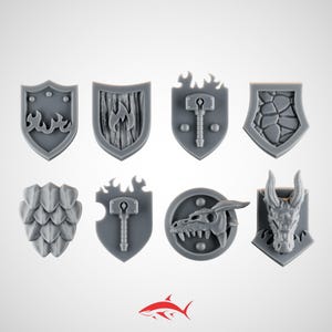 May include: A collection of eight gray fantasy-themed shield designs. The shields feature various emblems, including flames, a hammer, dragon scales, a dragon skull, and a dragon head. The shields are arranged against a white background.