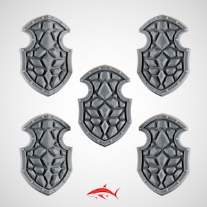 May include: Five gray, shield-shaped objects with a stone-like texture. Each shield has a decorative border with rivets. The shields are arranged on a white background. A red and white shark logo is at the bottom.