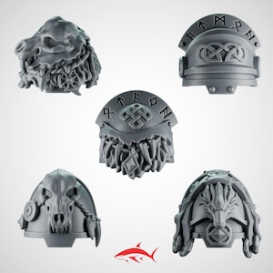 May include: Five gray miniature shoulder pads with detailed designs. The designs include a wolf skull, a wolf head, and helmets with runic inscriptions and Celtic knot patterns. The pieces are likely for a miniature wargame.