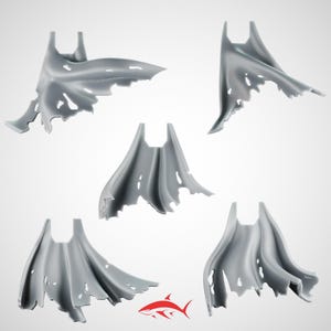 Op de afbeelding: Vijf grijze capes met gerafelde randen worden getoond tegen een witte achtergrond. De capes hebben een vloeiend ontwerp met gaten en scheuren, wat wijst op een versleten of beschadigd uiterlijk. Een rood haaienlogo staat in de rechter benedenhoek.