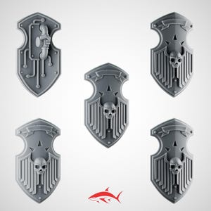 Könnte beinhalten: Fünf graue, schildförmige Miniaturen mit aufwendigen Designs. Vier Schilde weisen ein Totenkopfmotiv auf, während einer ein mechanisches Rohrdesign hat. Jeder Schild hat ein Banner oben. Wahrscheinlich für Tabletop-Spiele.