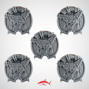 May include: Five gray, circular miniature shields with a wooden texture and a stone-like design in the center. Each shield has a decorative border and rope detailing. The shields are arranged against a white background.
