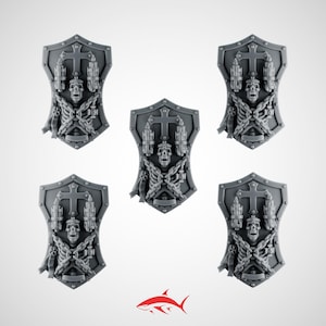 Peut inclure: Cinq boucliers miniatures gris ornés d'un crâne central, d'une croix, de deux torches et de chaînes drapées. Chaque bouclier présente un sommet et une base pointus avec une bordure rivetée. Le design est symétrique et détaillé en relief.