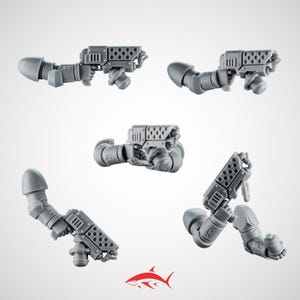 May include: Five grey plastic miniature gun models with attached arms, displayed against a white background. The guns have a detailed design with multiple holes and rectangular shapes. A red shark logo is in the bottom right corner.
