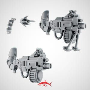 Może przedstawiać: Szare plastikowe miniaturowe bronie, w tym dwa karabiny maszynowe z pasami amunicji, pocisk i oddzielny pas amunicji. Karabiny maszynowe mają skomplikowane szczegóły mechaniczne.