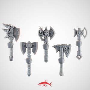 May include: Five grey fantasy axes with varied designs are displayed. One axe has a skull, another a dragon head, and others feature detailed elements. These miniature axes are likely for tabletop gaming or model building.