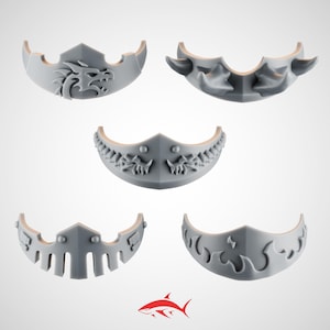 May include: Five gray decorative masks with various designs, including a dragon, horns, and flames. The masks are arranged against a white background, showcasing their intricate details and shapes. The masks are made of a light gray material.