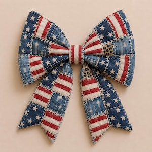 May include: A large, quilted bow featuring a patchwork design in red, white, and blue. The bow's design incorporates elements of the American flag, with stars and stripes. The bow is likely intended for decorative purposes.