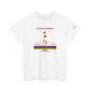 Pode incluir: Uma t-shirt branca de manga curta com um gráfico de um ciclista com os braços levantados. O texto diz THE ROAD WORLD CHAMPIONSHIPS, MONTREAL, 20-27 SEPTEMBER 2026. O design inclui um contorno de horizonte e faixas horizontais em azul, vermelho, preto, amarelo e verde.