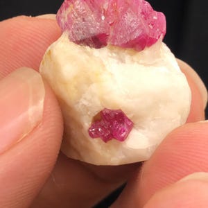 May include: A natural gemstone specimen with bright pink ruby crystals set in a creamy white matrix. The ruby crystals are a deep, saturated pink, and the matrix has a slightly rough texture. This unique piece is a beautiful example of natural mineral formations.