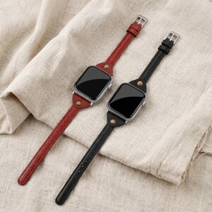 May include: Two leather watch bands, one red and one black, with silver-tone buckles and watch faces. The bands are attached to the watch faces with brass-colored rivets. The watch faces have black screens.
