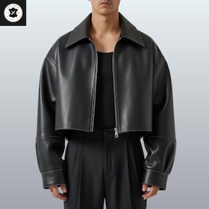 May include: Black leather jacket with a cropped design, featuring a collar, a silver zip, and white stitching details. The jacket has long sleeves with cuffs. The model is wearing a black top and black trousers.
