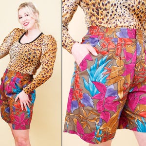 Op de afbeelding: Een vrouw draagt een top met luipaardprint met een zwarte halslijn en een korte broek met bloemenprint. De korte broek heeft een bruine basis met roze, paarse, blauwe en oranje bloemenpatronen. De outfit is in vintage stijl.