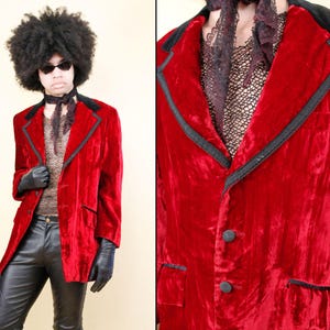 May include: A red velvet blazer with black trim and a black velvet collar. The blazer has two buttons and a pocket on each side.