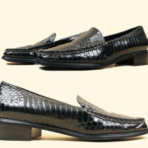 May include: A pair of black leather loafers with a snakeskin pattern. The loafers have a low heel and a pointed toe.