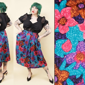 May include: A vintage floral print skirt in shades of blue, purple, red, and orange. The skirt is paired with a black blouse. The floral pattern is a bold, eye-catching design, perfect for a retro or bohemian look.