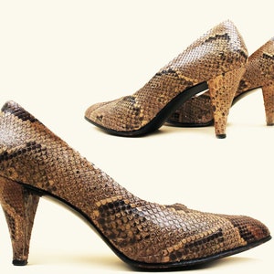 May include: A pair of brown and black snakeskin heeled pumps. The shoes have a pointed toe and a stiletto heel.