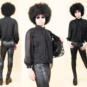 May include: A black ensemble featuring a sheer button-up shirt, a decorative vest with an openwork design, and form-fitting leather pants. The outfit is completed with platform boots. The overall style is retro and bold.