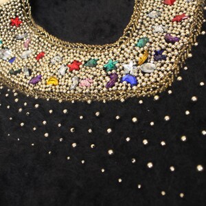 May include: Black fuzzy sweater with a silver beaded neckline decorated with colorful rhinestones and stars.