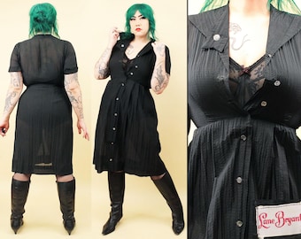 May include: A black button-down dress with a ruffled collar and a label that reads "Lane Bryant". The dress is made of a textured fabric and has a fitted bodice and a full skirt.