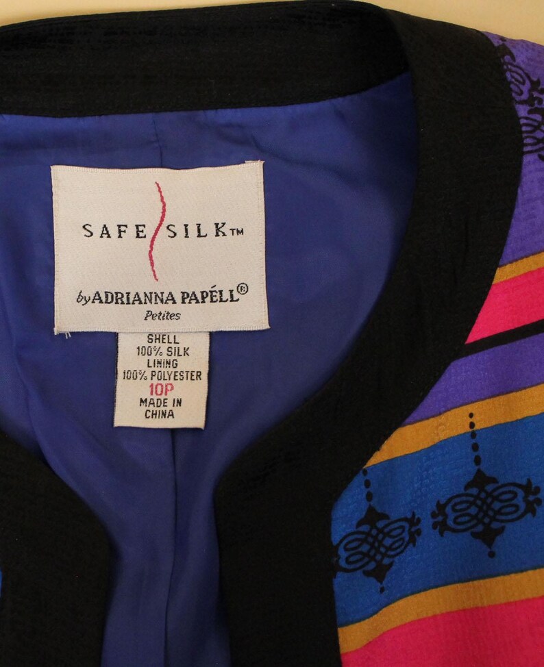 Może przedstawiać: Kurtka w czarno-niebieski wz&oacute;r z białą metką z napisem "SAFE SILK&trade; by ADRIANNA PAPELL&reg; Petites SHELL 100% SILK LINING 100% POLYESTER 10P MADE IN CHINA"