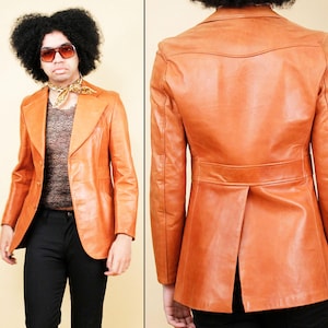 May include: A vintage orange leather blazer with a notched collar and two front pockets. The blazer has a single-button closure and a tailored fit. The back of the blazer features a vent at the hem. The jacket is shown on a person wearing black pants.