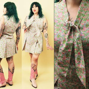 Könnte beinhalten: Ein weißes Kleid mit Blumenmuster und einer Schleife am Hals. Das Kleid hat einen Faltenrock und ist ärmellos. Das Model trägt rosa Cowboystiefel.