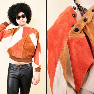 May include: A vintage suede jacket in a patchwork design with orange, brown, and cream panels. The jacket is cropped with a ribbed brown hem and cuffs. The outfit includes black leather trousers.